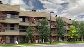 A multi-story building with balconies, outdoor seating, and a stone facade.