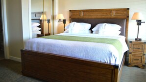 A neatly made bed with a wooden headboard, two bedside lamps, and a small wooden nightstand with drawers.