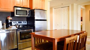 A kitchen with stainless steel appliances, wooden cabinets, and a dining table with chairs.