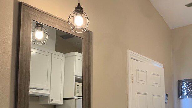 A hallway with a wooden table and two stools, a large mirror, and a door. - Newly redone studio w/outdoor lawn & eating space (Azusa)