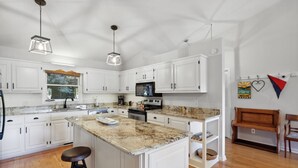 A modern kitchen with white cabinets, granite countertops, and pendant lighting. - Lake front home (Hiawassee)