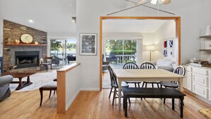A spacious living room with a fireplace, a dining area with a large table and chairs, and a view of the outdoors through a sliding glass door. - Lake front home (Hiawassee)