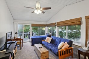 A spacious room with a large sectional sofa, a wooden coffee table, a TV, and a ceiling fan.