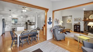 A spacious living area with a fireplace, a dining area with a large island, and a kitchen with white cabinets and a ceiling fan. - Lake front home (Hiawassee)