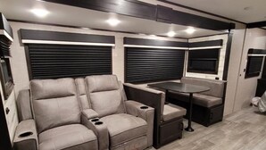 A compact RV interior with a sofa, a small table, and a window.