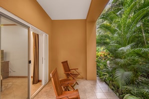 A room with a sliding glass door leading to a balcony with a view of tropical plants.