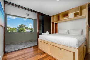 Relax in this serene bedroom with a bed and sliding door to an outdoor area offering a view of lush greenery.