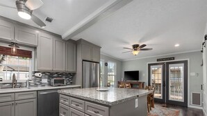 A modern kitchen with grey cabinets, a granite countertop, and a built-in microwave. - Cheerful 3 Bedroom Home with Loft (Dickinson)