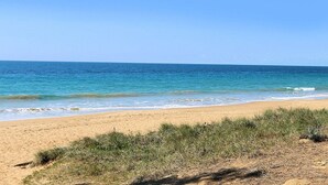 Een strand met helderblauw water en een zandstrand.