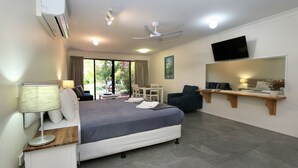 Een hotelkamer met een bed, een bureau, een stoel, een televisie en een balkon met uitzicht.