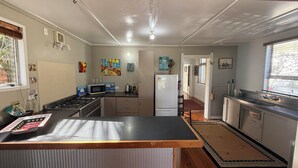 Una cocina con una isla central, microondas, estufa y refrigerador.