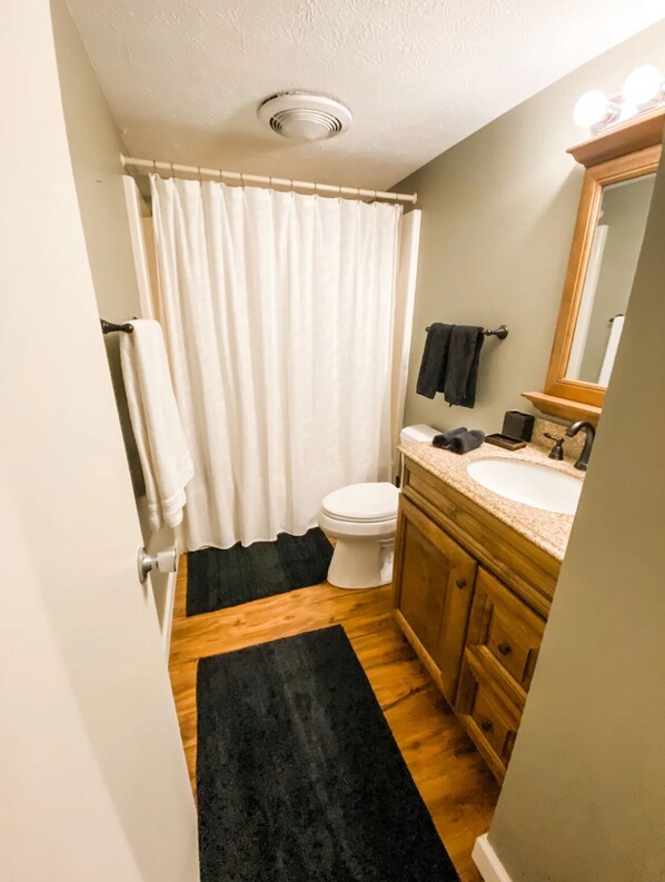 A compact bathroom with a toilet, sink, and mirror.