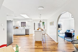 Una cocina moderna con armarios blancos, una isla central y un comedor con vistas.
