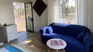A room with a blue sofa, a small white table, a refrigerator, and a glass door leading outside.