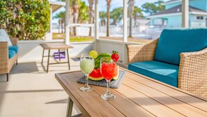 A covered outdoor seating area with wicker furniture and a table with drinks.
