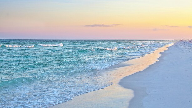 A beach with waves and a clear sky.
