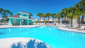 A swimming pool with a 4 ft depth marker, surrounded by palm trees and a covered seating area.