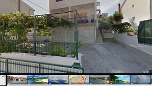 A residential street with a white building, a green fence, and a staircase leading to a balcony. - Beautiful Apartment with Sea View, Trogir, Croatia (Mastrinka)