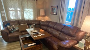 Un salon avec un canapé en cuir marron, une table basse en bois et une table d’appoint avec une lampe.