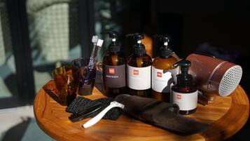 Un plateau en bois contenant divers produits de soins personnels, notamment un gel douche, un shampooing, un après-shampooing et un sèche-cheveux.