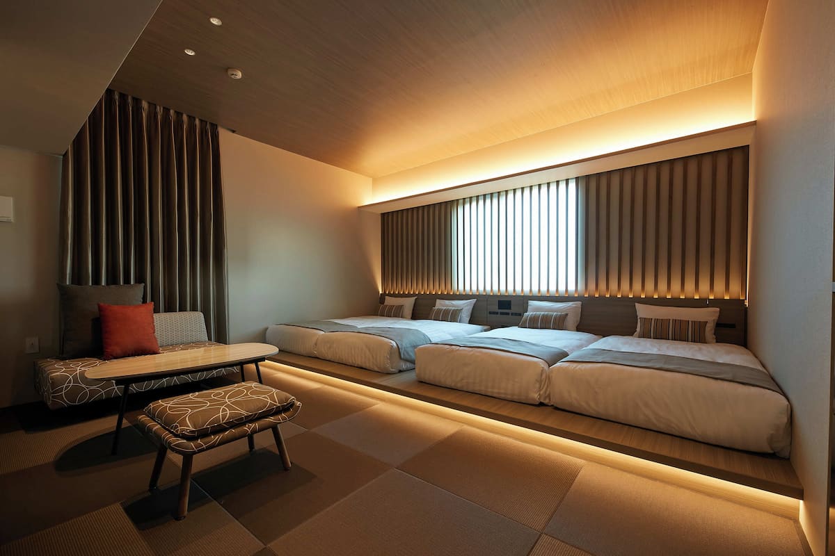 A modern hotel room with a sofa bed, a small table, and a bench.