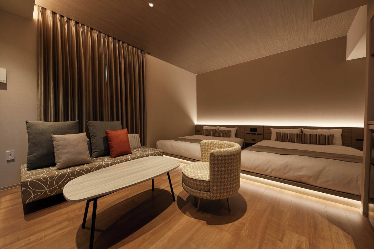 A modern hotel room with a sofa, a small table, a chair, and a bed.