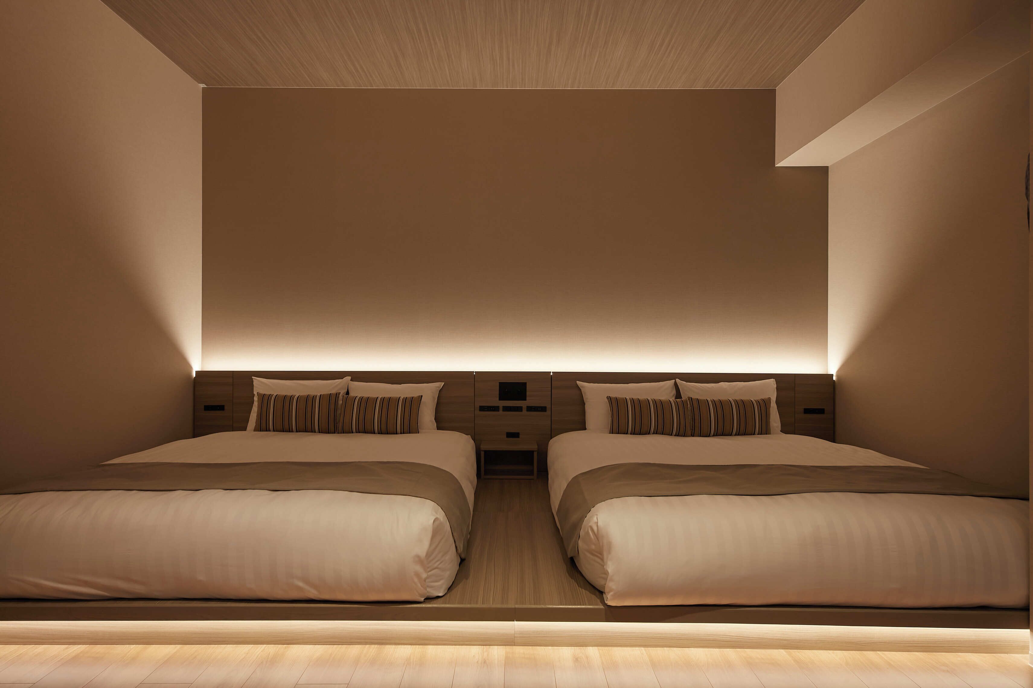 Ein modernes Hotelzimmer mit zwei Betten, Holzboden und minimalistischem Design.