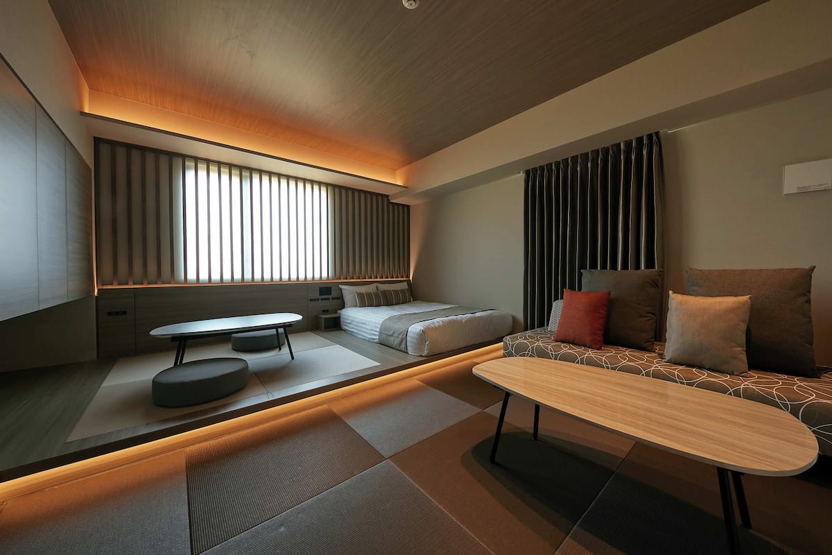 A modern, well-lit room with a sofa, a small table, and a bed.