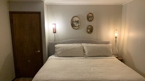 A bedroom with a bed, a door, and wall-mounted picture frames.