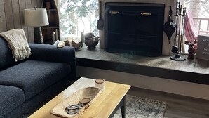 A living room with a sofa, a coffee table, a fireplace, and a television.