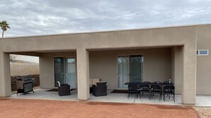 Un patio couvert comprenant un barbecue, du mobilier d’extérieur et une porte-fenêtre coulissante.