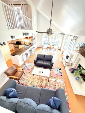 A modern living space with a sofa, coffee table, and a dining area with chairs and a table. - LA Tortuga, Beachside house in sought after Pirates Beach, Galveston TX (Galveston)
