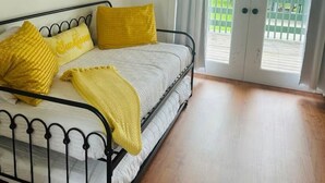 A bedroom with a bed, yellow pillows, a round painting, and a sliding glass door to a balcony.