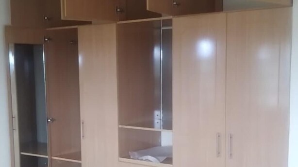 Een kamer met een grote houten garderobe, een spiegel en een betegelde vloer.