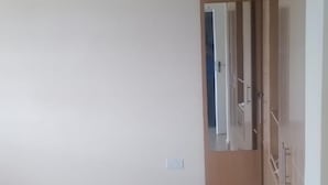 Een ruime kamer met een betegelde vloer, een houten kast en een deur naar een andere kamer.
