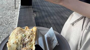 A person holding a sandwich with a side of fries and a drink.