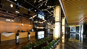A modern hotel lobby with a reception desk, a long reception counter, and a row of potted plants. - Paradise hotspring hotel (Chenzhou)