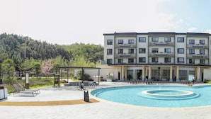 A hotel with a swimming pool, outdoor seating, and a garden area. - Paradise hotspring hotel (Chenzhou)