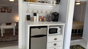 A compact kitchen with a microwave, coffee maker, and various kitchen utensils on shelves. - Charming Country Cottage- Long Term Stays Welcome! (Eden)
