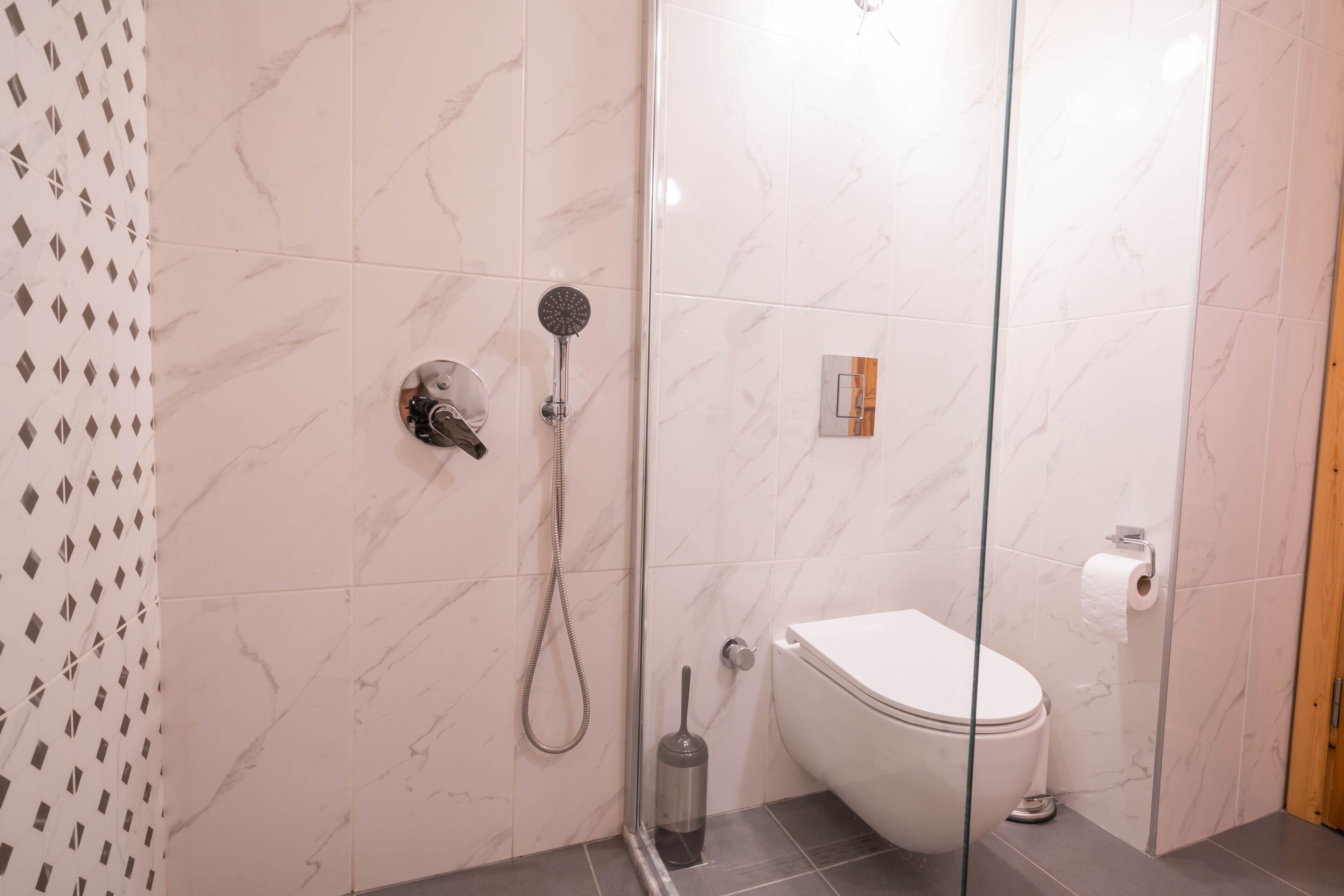A bathroom with a shower, toilet, and a glass-enclosed shower stall.