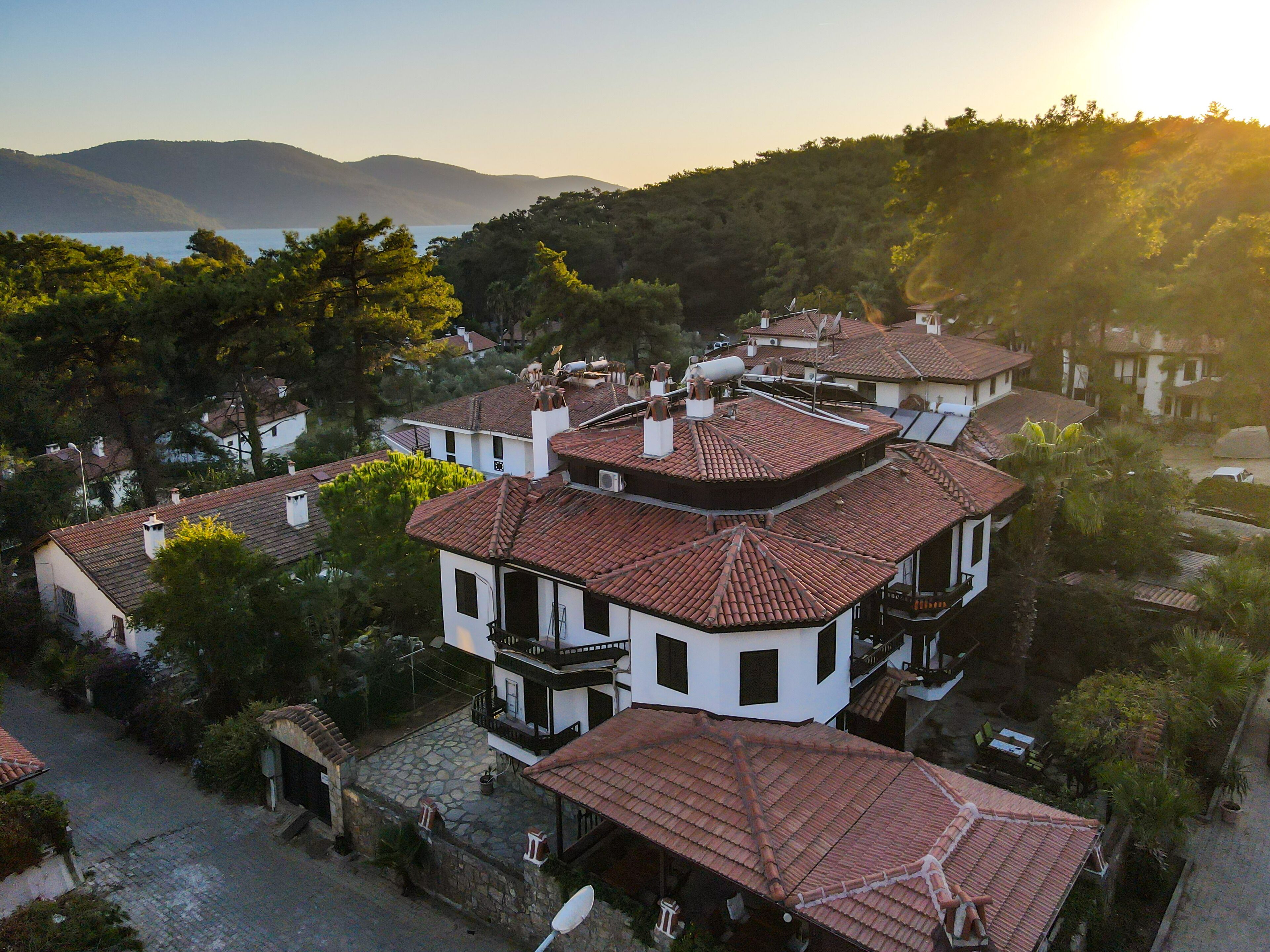 A residential area with terracotta-tiled roofs, white exteriors, and a hillside backdrop.