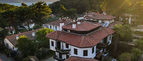 Un barrio residencial con tejados de tejas rojas, fachadas blancas y un paisaje montañoso de fondo.