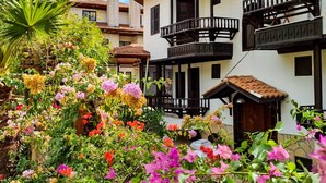 Un edificio tradicional con varios balcones y un jardín lleno de flores.