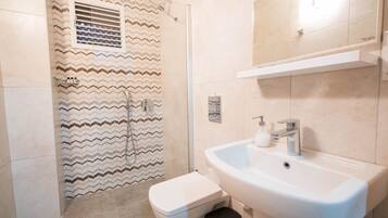 A bathroom with a shower, toilet, and sink.