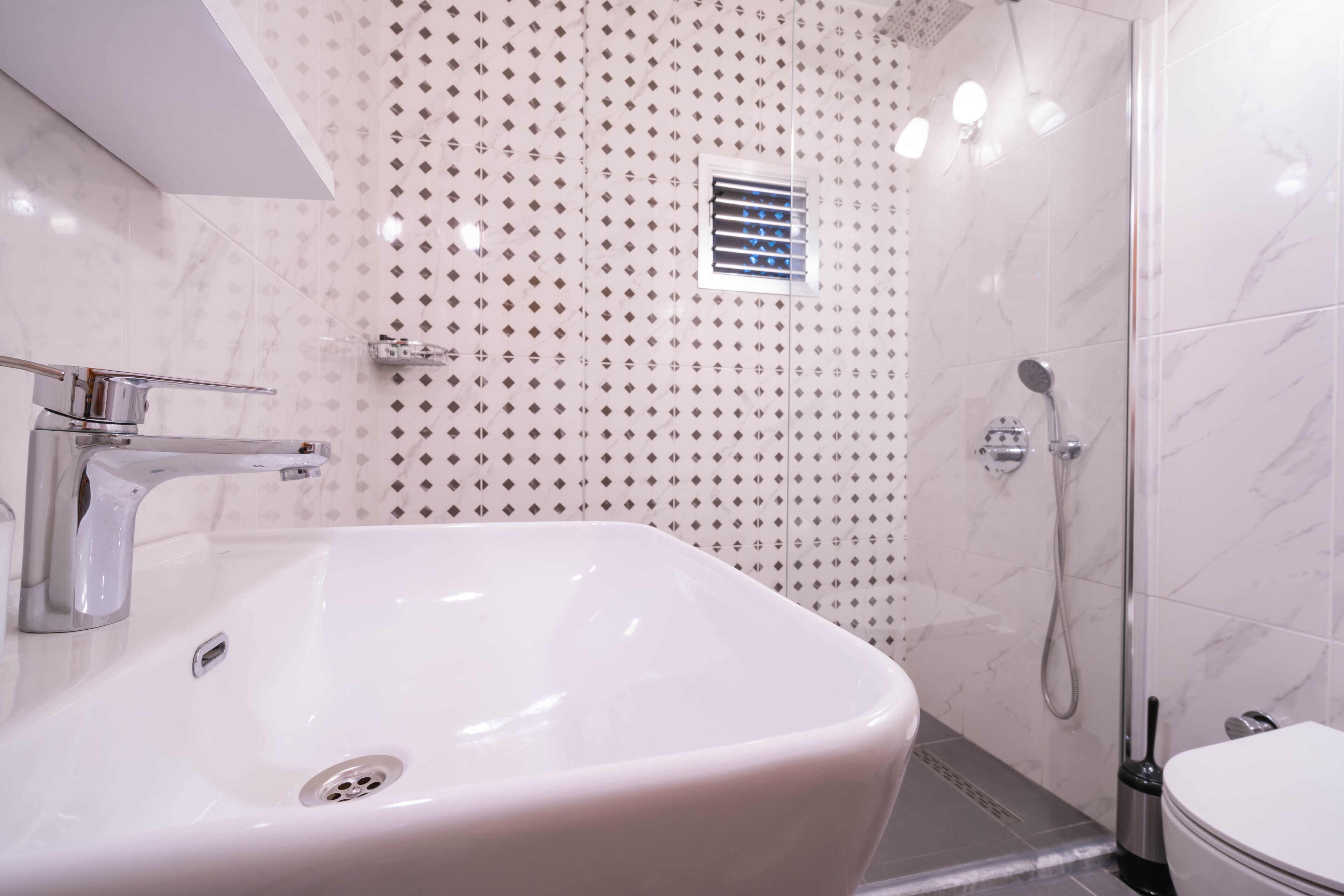 Un baño moderno con lavamanos blanco, ducha e inodoro.