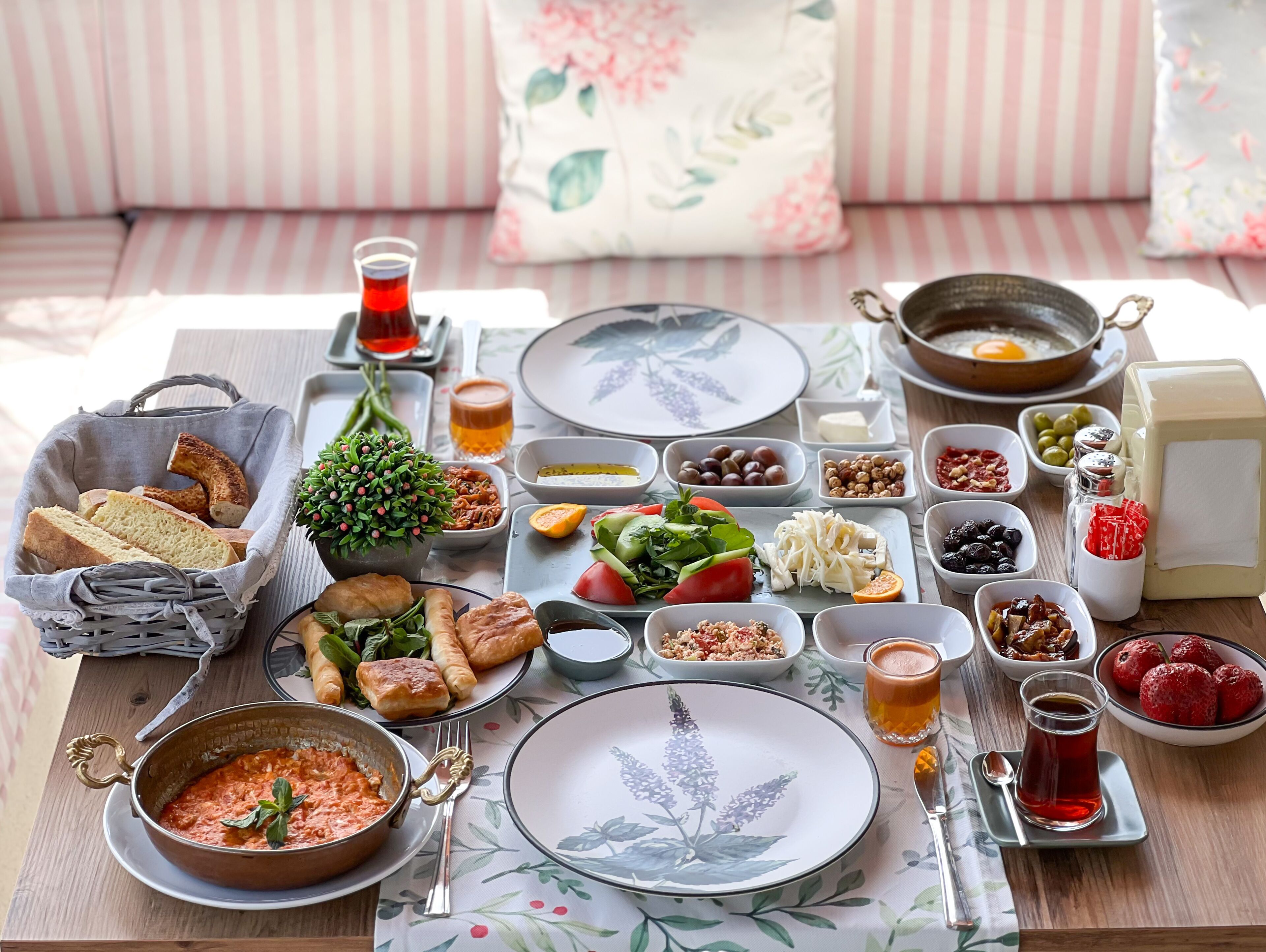 A breakfast table with various dishes, including bread, pastries, and a bowl of soup.
