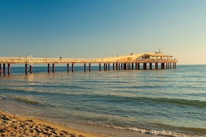 Un muelle que se adentra en el agua con un edificio encima, sostenido por postes de madera.