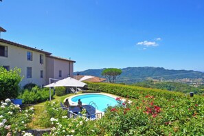 Piscina com vista para uma casa e colinas.