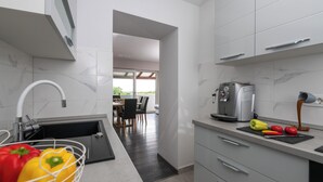 Una cucina moderna con lavandino, piano di lavoro e zona pranzo visibile sullo sfondo.