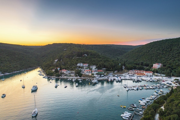 A marina with boats, a coastal town, and hills in the background.